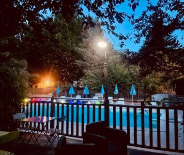 Piscine extérieure éclairée au crépuscule avec parasols au Flower Camping La Pibola