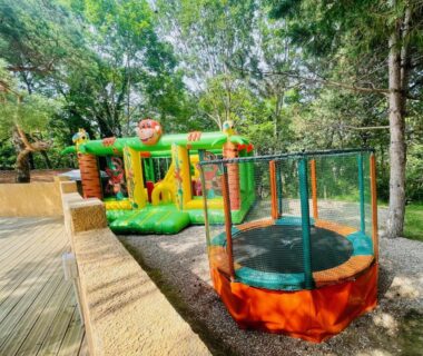Aire de jeux extérieure avec château gonflable et trampoline au Flower Camping La Pibola