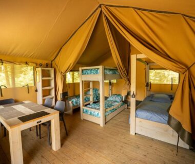 Intérieur de tente avec lits superposés et coin repas au Flower Camping La Sténiole