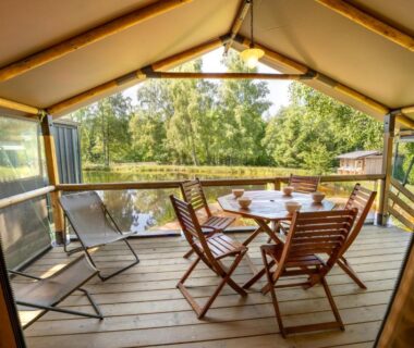 Terrasse couverte avec table et chaises donnant sur l'étang du Flower Camping La Sténiole