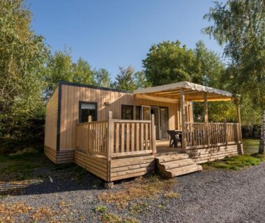 Terrasse en bois d'un mobil-home entourée de bouleaux au Flower Camping La Sténiole