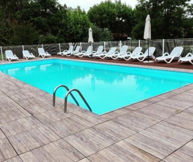 Piscine extérieure avec chaises longues et parasols au camping Frédéric et Maëva