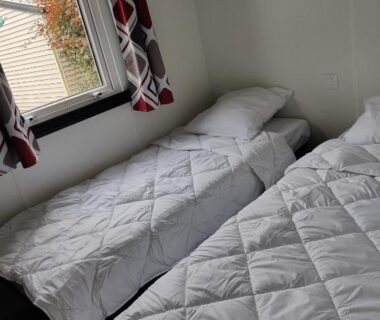 Chambre avec deux lits simples et fenêtre dans le mobil-home Frédéric et Maëva