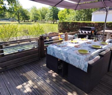 Terrasse en bois avec table dressée et parasol au camping Fun et Nature