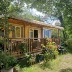 Terrasse en bois et façade sous arbres du GC Confort et détente