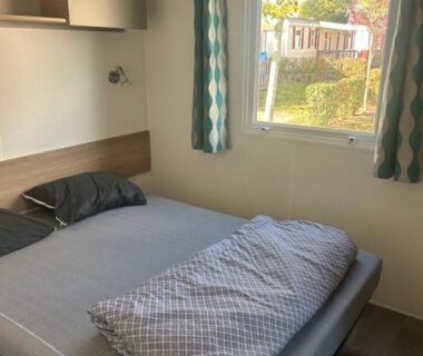 Chambre avec lit double et fenêtre sur le camping du GRS Mobil Home