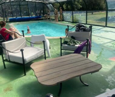 Piscine couverte avec fauteuils et table au camping Gard les Dolmens