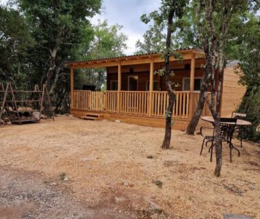 Terrasse en bois ombragée dans les pins au camping Gard les Dolmens