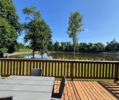 Terrasse en bois avec table et chaises face à l'étang du Gîte avec son SPA privatif