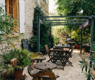 Terrasse en pierre avec tables et pergola au Gîte et chambres d'Hôtes de Cozance
