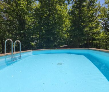 Piscine extérieure entourée d'arbres au Gite la bleuet avec piscine