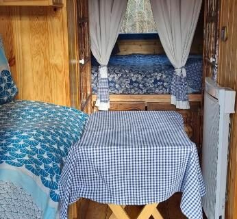 Intérieur en bois avec lit table et rideaux dans le Gite la bleuet avec piscine