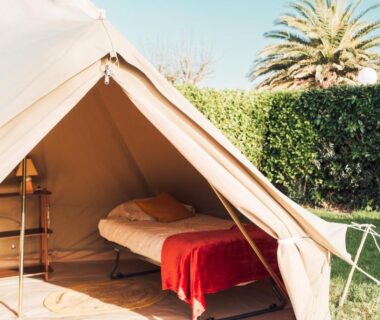 Intérieur de tente avec lit et couverture rouge au Glamping Spot Penmarch