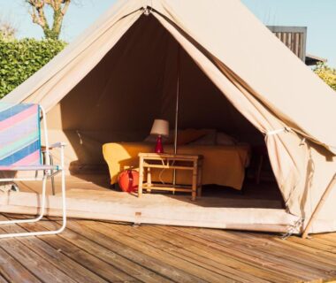 Terrasse en bois avec tente glamping ouverte et fauteuil au Glamping Spot – Penmarch
