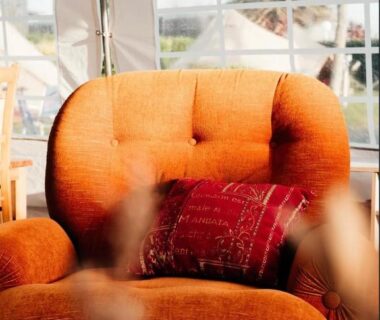 Intérieur de tente avec fauteuil orange et coussin dans le Glamping Spot - Penmarch