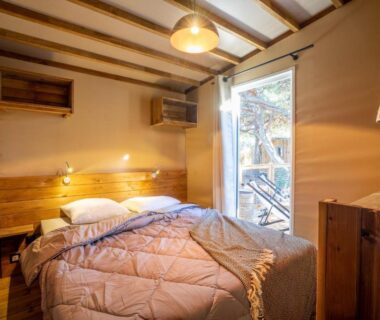 Chambre avec lit double et porte-fenêtre ouvrant sur terrasse au Glamping Terre & Mer