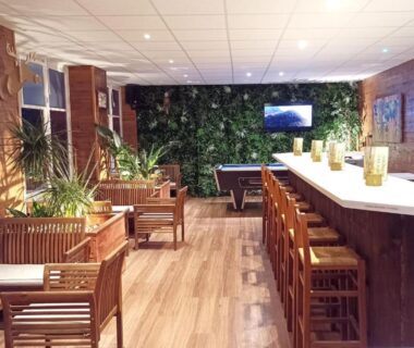 Salon intérieur avec comptoir tabourets et plantes au Glamping Terre & Mer