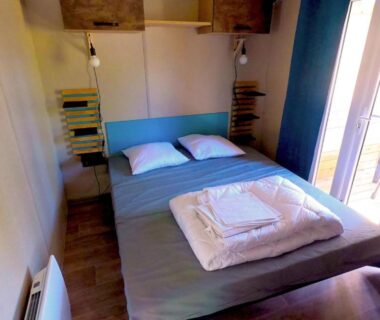 Chambre avec lit double et porte-fenêtre donnant sur balcon au Glamping Terre & Mer