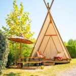 Terrasse en bois avec parasol et chaises devant tente tipi au Glamping Urrugne