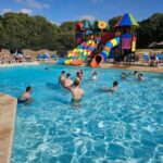 Piscine extérieure avec toboggans colorés et baigneurs au camping Glenan01