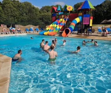 Piscine extérieure avec toboggans colorés et baigneurs au camping Glenan01