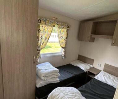 Intérieur mobil-home avec deux lits et rideaux fleuris du Glenan01