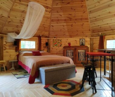 Intérieur de lodge en bois avec lit et moustiquaire dans Graines de nature Ecolodges Insolites