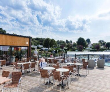 Terrasse en bois avec tables et piscine du Grand MobilHome