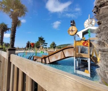 Piscine extérieure avec toboggans et palmiers dans le camping Grand MobilHome