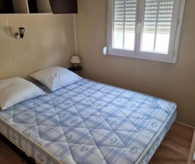 Chambre avec lit oreillers et lampe dans le Grand Mobile home