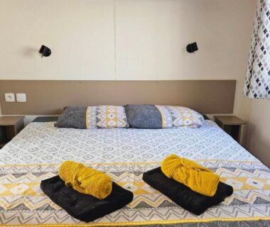 Chambre avec lit double et serviettes dans le Grand mobil-home n°604 3ch tout confort au calme
