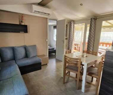 Salon avec canapé et coin repas dans le Grand mobil-home numéro 604 3ch tout confort au calme