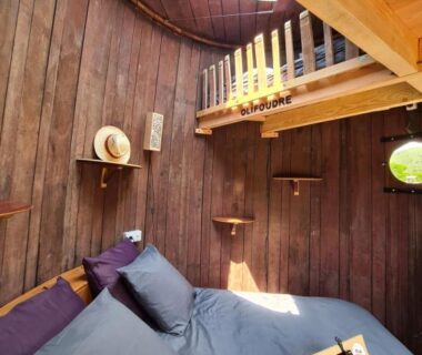 Intérieur de cabane en bois avec lit hublot et mezzanine dans l'hébergement Foudreaterre