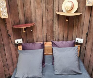 Intérieur chambre en bois avec lit et étagères dans l'hébergement insolite Foudreaterre