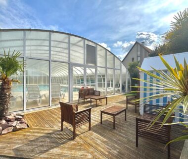 Terrasse en bois avec chaises et piscine couverte de l'hébergement MERVILLE FRANCEVILLE