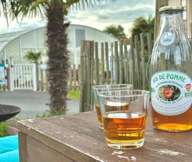 Terrasse en bois avec bouteille et verres devant piscine couverte à l'hébergement bord de mer MERVILLE FRANCEVILLE