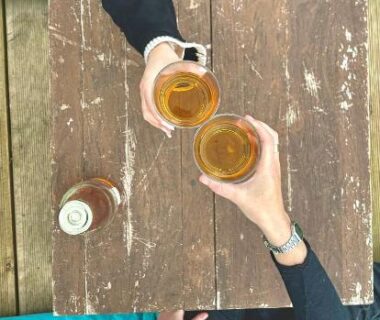 Terrasse en bois avec deux verres levés au-dessus d'une table à l'Hébergement bord de mer MERVILLE FRANCEVILLE