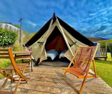 Terrasse en bois avec chaises et tente glamping ouverte montrant deux lits de l'hébergement Hébergement bord de mer MERVILLE FRANCEVILLE