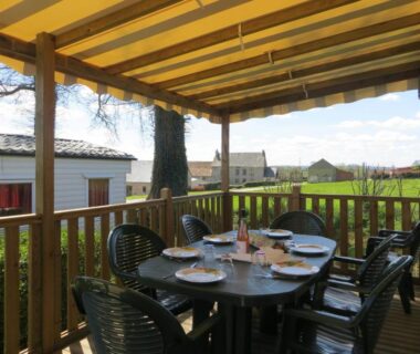 Terrasse couverte avec table et chaises dans l'hébergement Hebergement dans un Domaine à Litteau