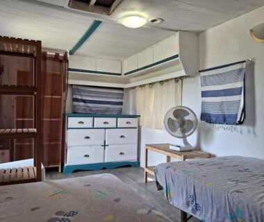 Intérieur de chambre avec lit commode et ventilateur dans les Hébergements bohêmes pleine nature