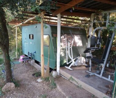 Emplacement ombragé avec caravane et matériel de sport aux Hébergements bohêmes pleine nature