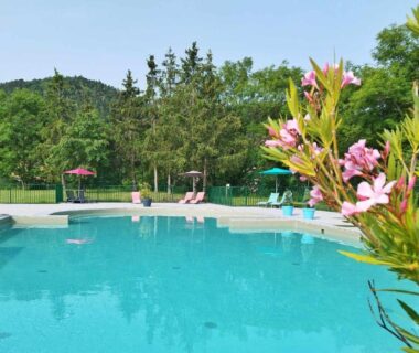 Piscine extérieure avec transats et parasols dans le camping Hotel De Plein Air Le Chanset