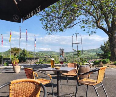 Terrasse extérieure avec tables chaises et boissons face à la vallée au Hotel De Plein Air Le Chanset