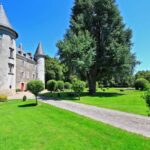 Parc verdoyant et château vus depuis l'allée à l'Hôtellerie de Plein Air Camping Leychoisier