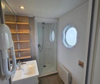 Salle de bain avec douche cabine et hublot dans le Mobilhome cosy Houlgate-154 Camping 5 étoiles