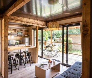 Salon avec cuisine ouverte et terrasse vitrée dans le chalet Huttopia Arcachon