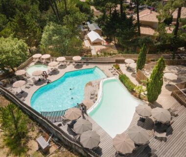 Piscine extérieure avec deux bassins parasols et transats au camping Huttopia Arcachon