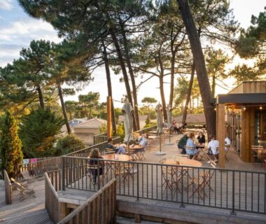 Terrasse en bois avec tables et pins au Huttopia Arcachon