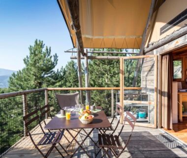 Terrasse en bois avec table et chaises sur balcon panoramique du Huttopia Dieulefit