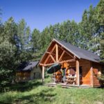 Chalet en bois sur pelouse entouré de pins au camping Huttopia Font Romeu